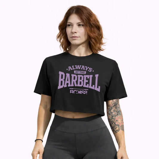 Modelo mujer con crop top Always at the Barbell Rckiss, vista frontal tatuajes florales, pantalón deportivo gris, mujer fitness gym crossfit