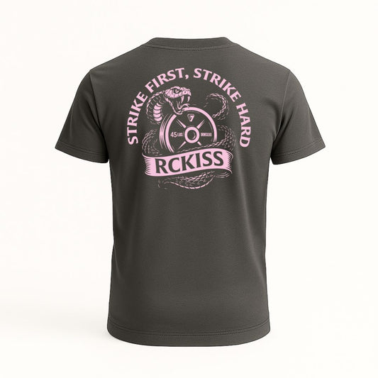Playera gris con diseño trasero de serpiente enrollada en un disco de pesas de 45 lbs, con el texto “Strike First, Strike Hard” y “RCKISS” en rosa. Estética agresiva y poderosa.